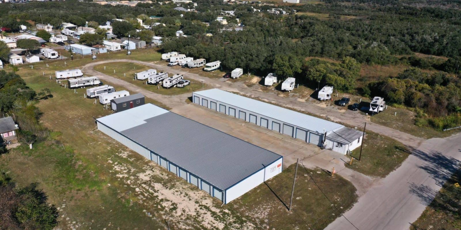 Aransas Pass RV Park and Storage Aerial view of Aransas Pass RV and Storage showing spacious RV sites, secure white storage buildings, trees, and nearby residences.