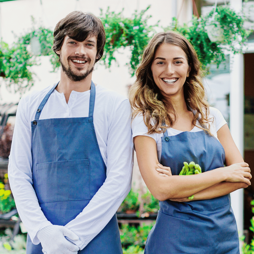 Two smiling gardeners with aprons.