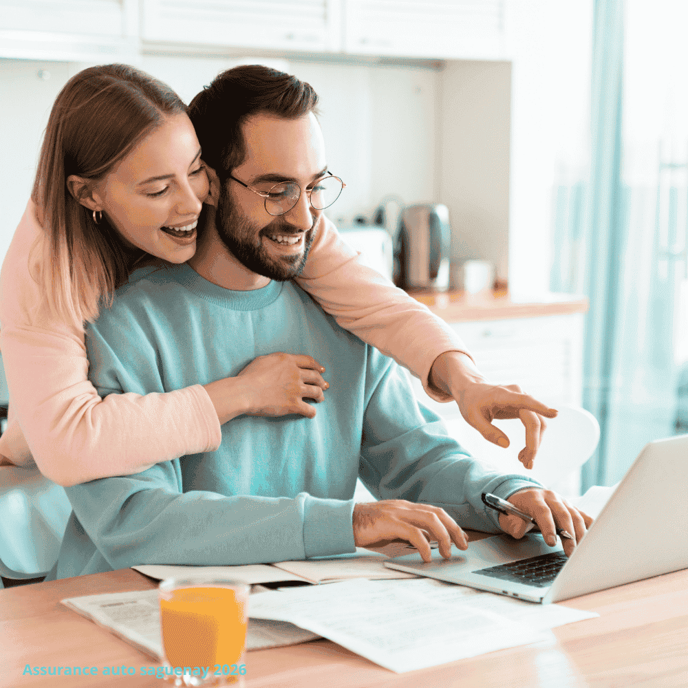 un couple souriant est assis à une table de cuisine avec de la paperasse et un ordinateur portable, explorant l'assurance auto à saguenay. la femme enlace l'homme par derrière alors qu'ils regardent l'écran ensemble. un verre de jus d'orange est posé sur la table. Saguenay la meilleur soumission d'assurance auto