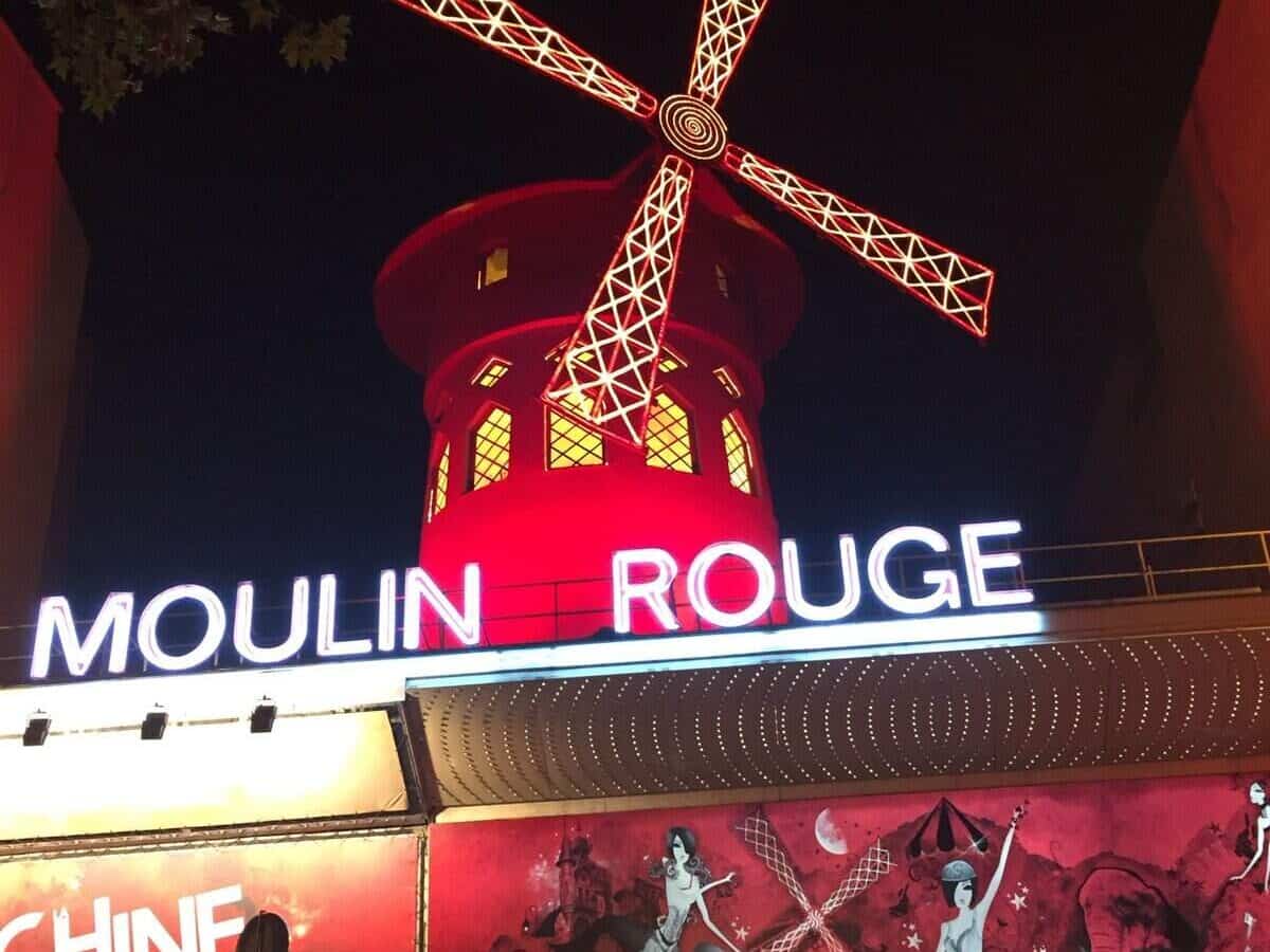 The outside of the Moulin Rouge in Paris, with its iconic red windmill.  The Moulin Rouge should not be missed on a Paris girls' trip.