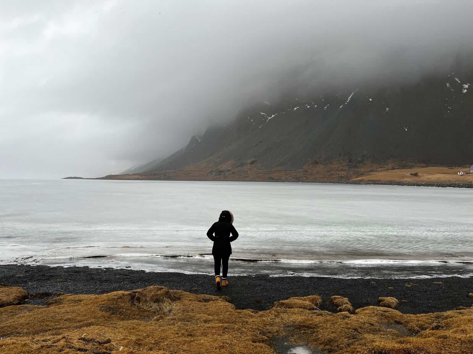 A woman standing on a black sand beach in Iceland.