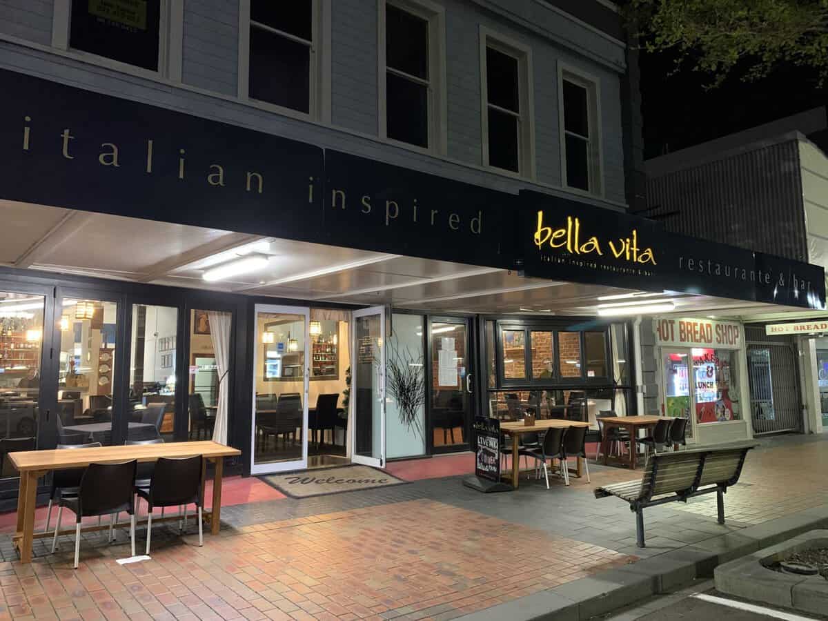Bright evening view of Bella Vita Italian restaurant and bar with inviting outdoor seating on a sidewalk.
