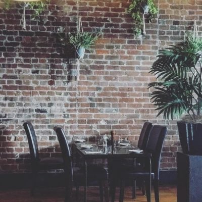 Relaxed dining area with exposed brick wall, greenery, and modern decor at Bella Vita.