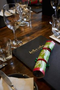 Elegant dining table setup with wine glasses and Bella Vita menu in NZ.