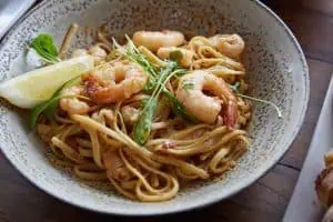 Shrimp seafood pasta with lemon and greens in a rustic bowl, perfect for Italian dining.