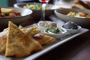 Delicious Indian paneer naan with chutneys and dips on a white platter.