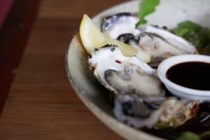 Fresh oysters with lemon wedge and dipping sauce at Bella Vita restaurant New Zealand.