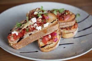 Fresh gourmet bruschetta with tomato, basil, feta, and balsamic glaze on toasted artisan bread.