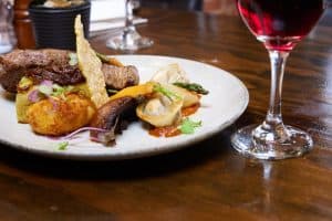 Gourmet steak and seafood dish with red wine at Bella Vita restaurant NZ.