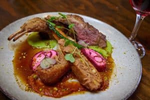 Succulent roasted lamb with gourmet vegetables and vibrant plating.