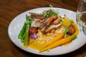 Fresh seafood dish with prawns, fish, asparagus, carrots, and saffron sauce at Bella Vita NZ.