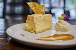 Delicious cheesecake with caramel sauce and edible flower garnish.