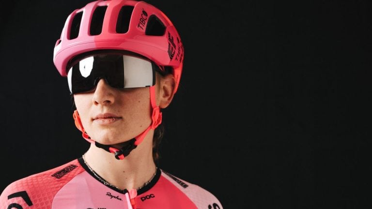 Coperto stilizzato, ciclismo femminile, caschetto rosa e occhiali da sole sportivi, abbigliamento professionale da ciclista, bici che amore, abbigliamento ciclismo rosa, passione per il ciclismo femminile, accessori ciclismo professionali, materiali di alta qualità per ciclisti femminili, dettagli di abbigliamento bici che amore, componenti biciclette sportive, presentazione ciclista donna con attrezzatura tecnica.