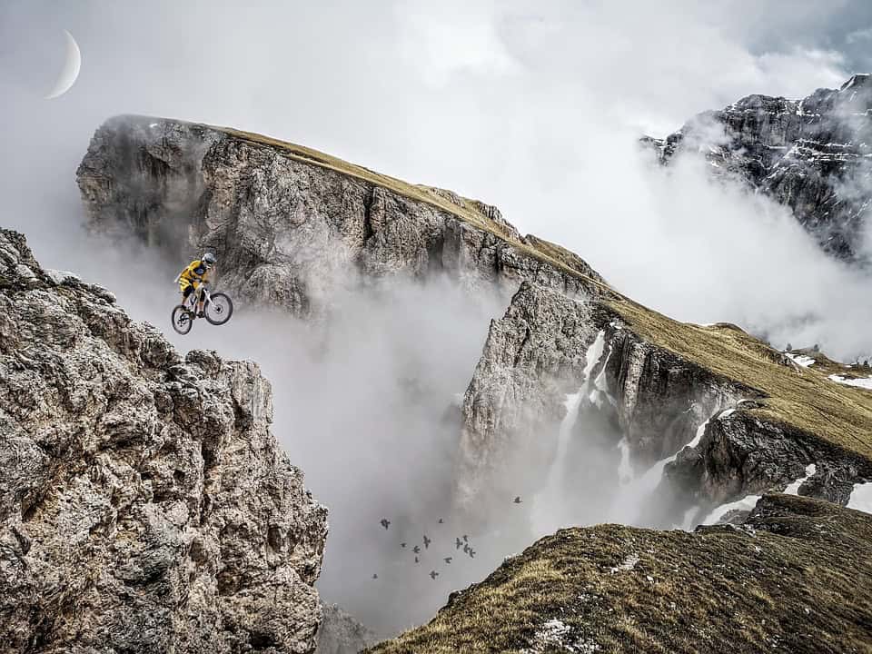 Una bici da mountain bike che affronta un percorso impegnativo tra le montagne, circondata da nebbia e paesaggi spettacolari, perfetta per gli appassionati di ciclismo outdoor e avventure estreme.