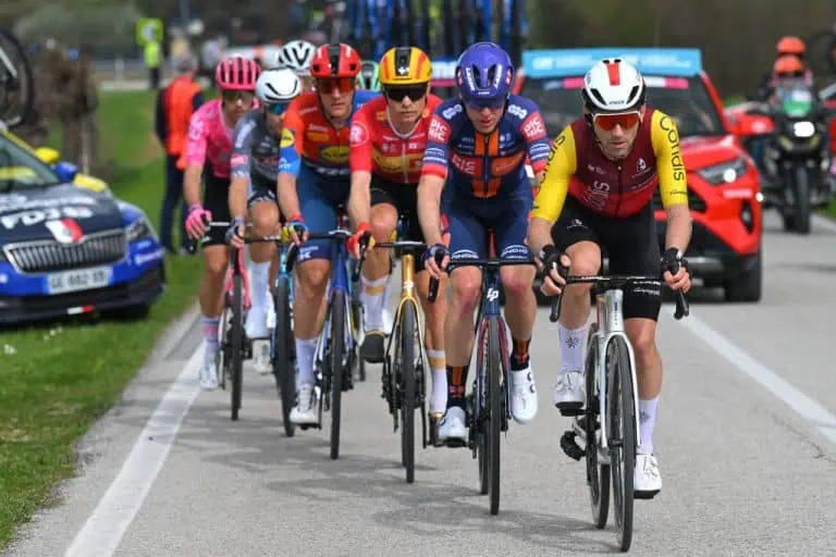 Ciclisti professionisti che partecipano a una gara su strada, in gruppo, con supporto di auto e Moto, sulla strada di campagna durante una competizione ciclistica.