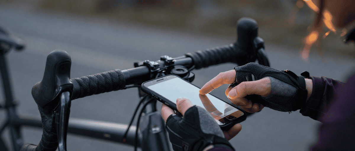 Mani con guanti da ciclismo invernali che usano uno smartphone