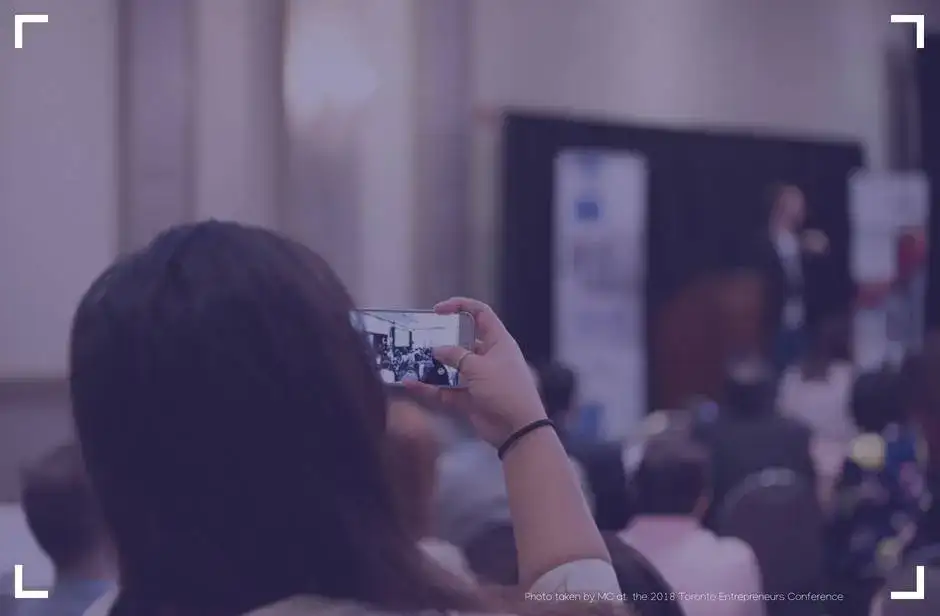 girl with dark hair taking a photo of stage with phone