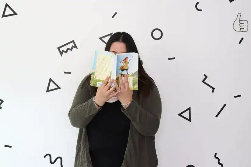 Person reading a book with geometric shapes on the wall behind.
