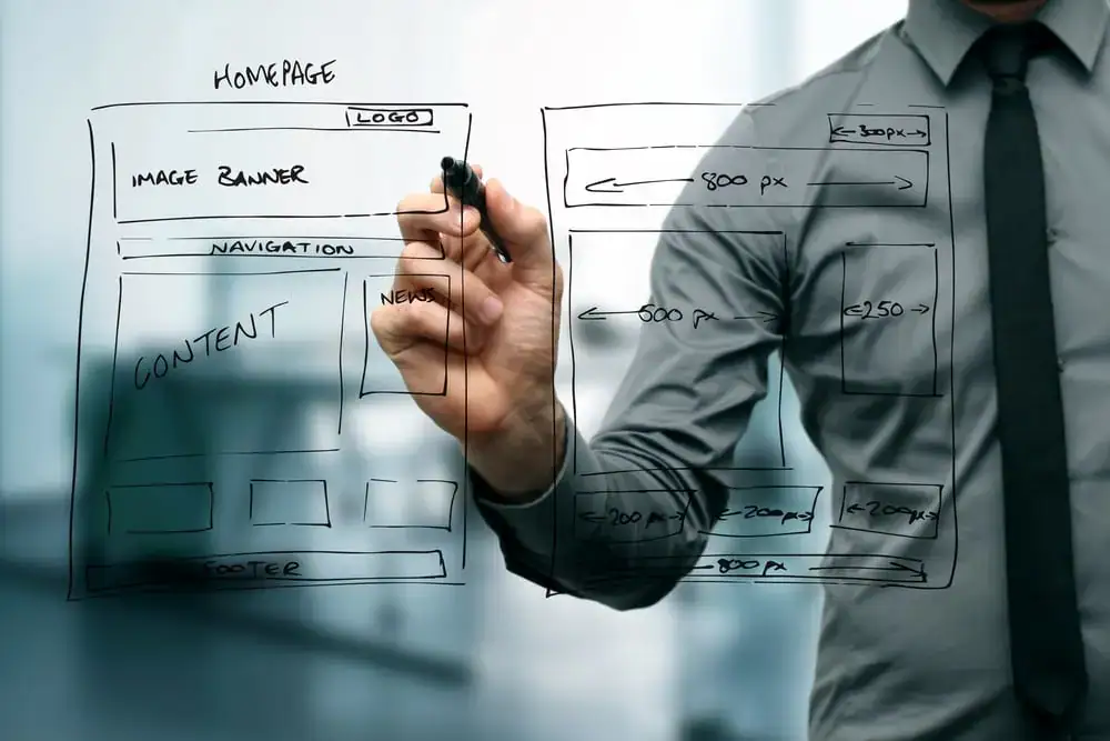 Business professional designing website wireframe on transparent glass board.