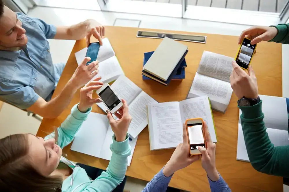 Students capturing notes and books with smartphones during a study session.