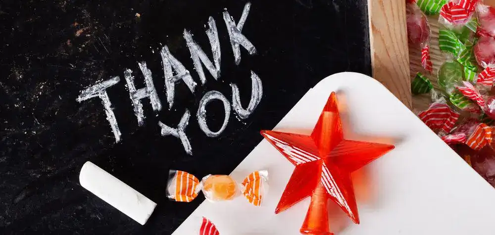 Thank you message written on a chalkboard with candy and a star-shaped decoration.