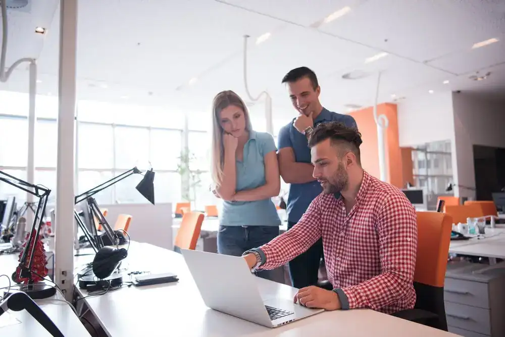 Team collaborating on a laptop in a modern office environment, discussing project ideas and strategi.