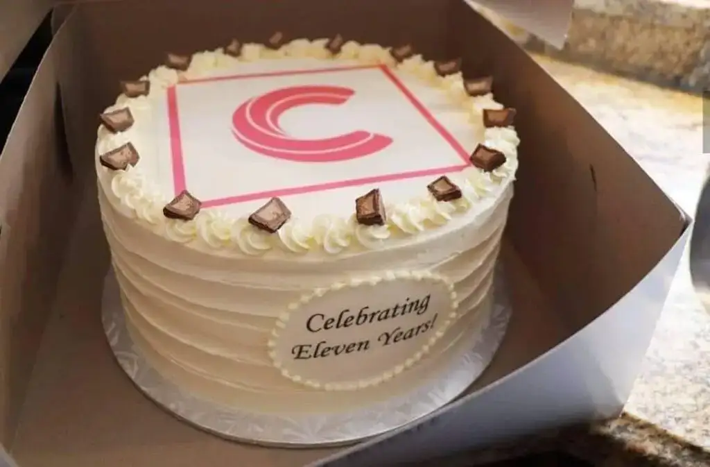 Celebration cake featuring a pink logo and "Celebrating Eleven Years" message, perfect for milestone.
