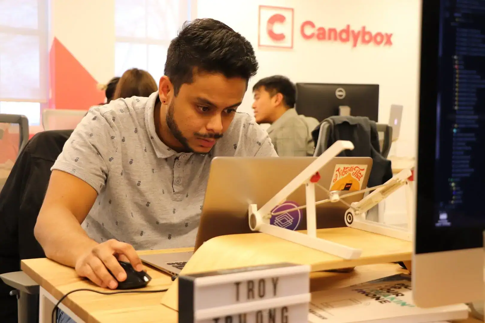 Young man working on laptop in modern office environment.