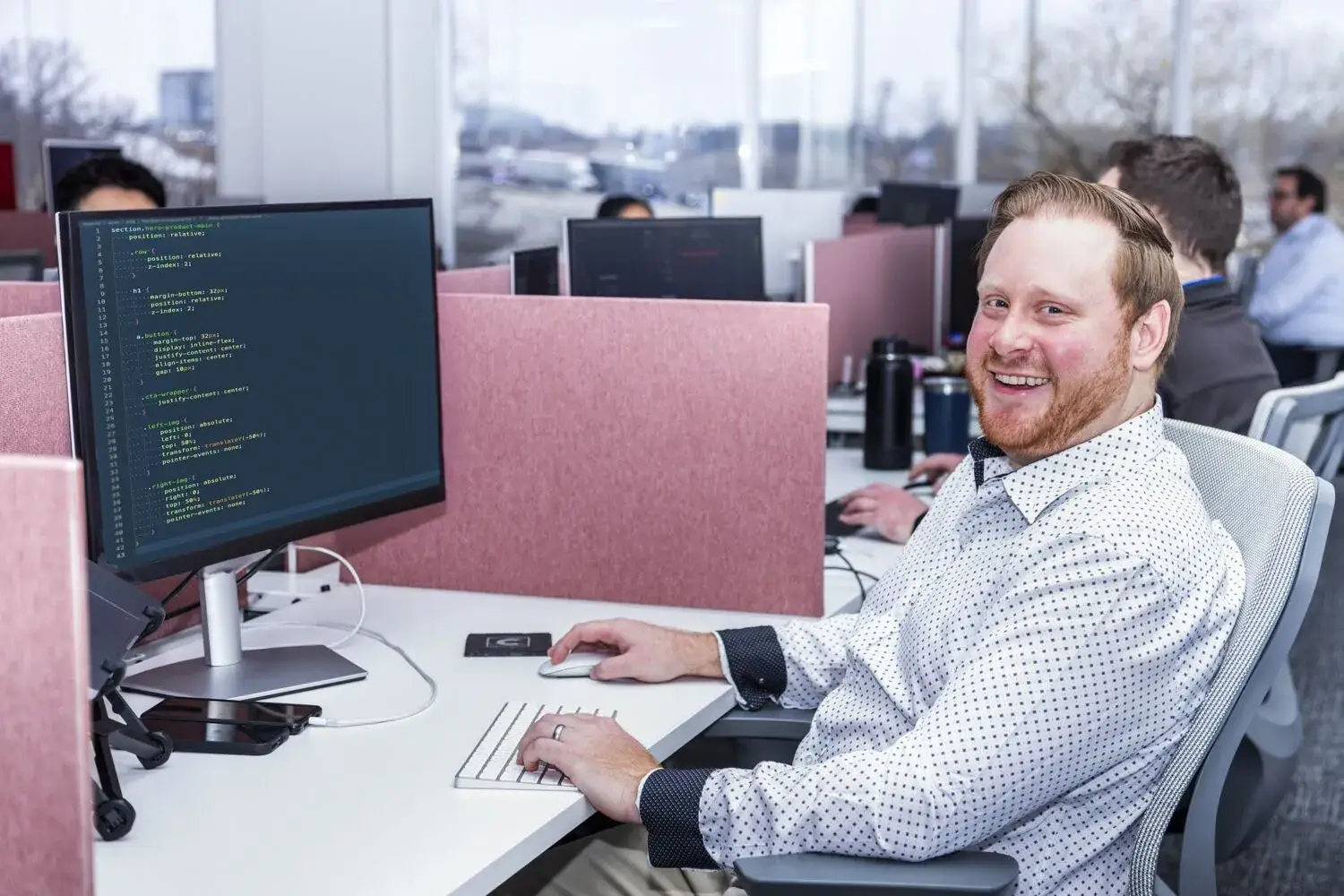 Software developer working on code at a modern office desk.