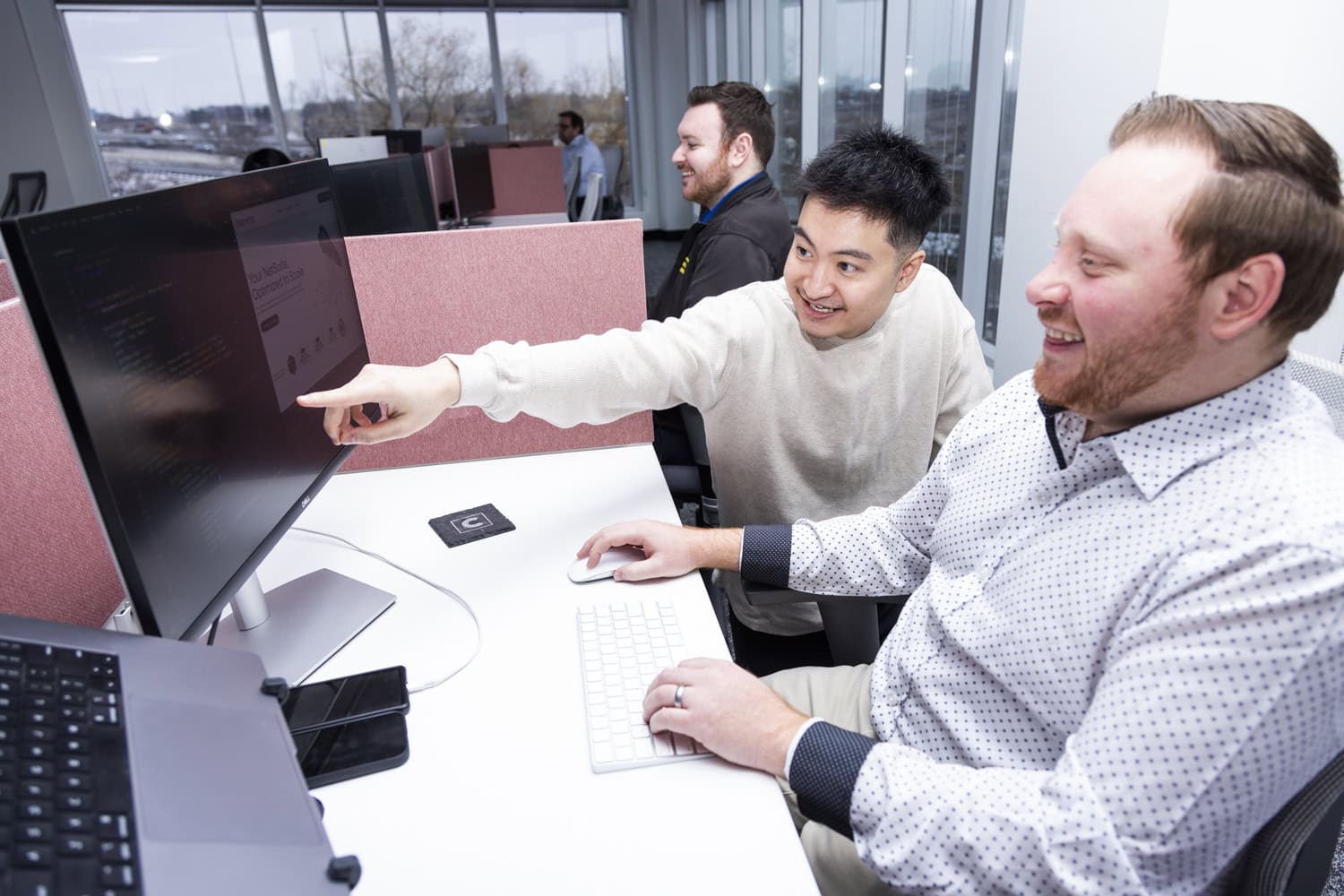 Two young financial analysts working together at a modern office desk with computers.