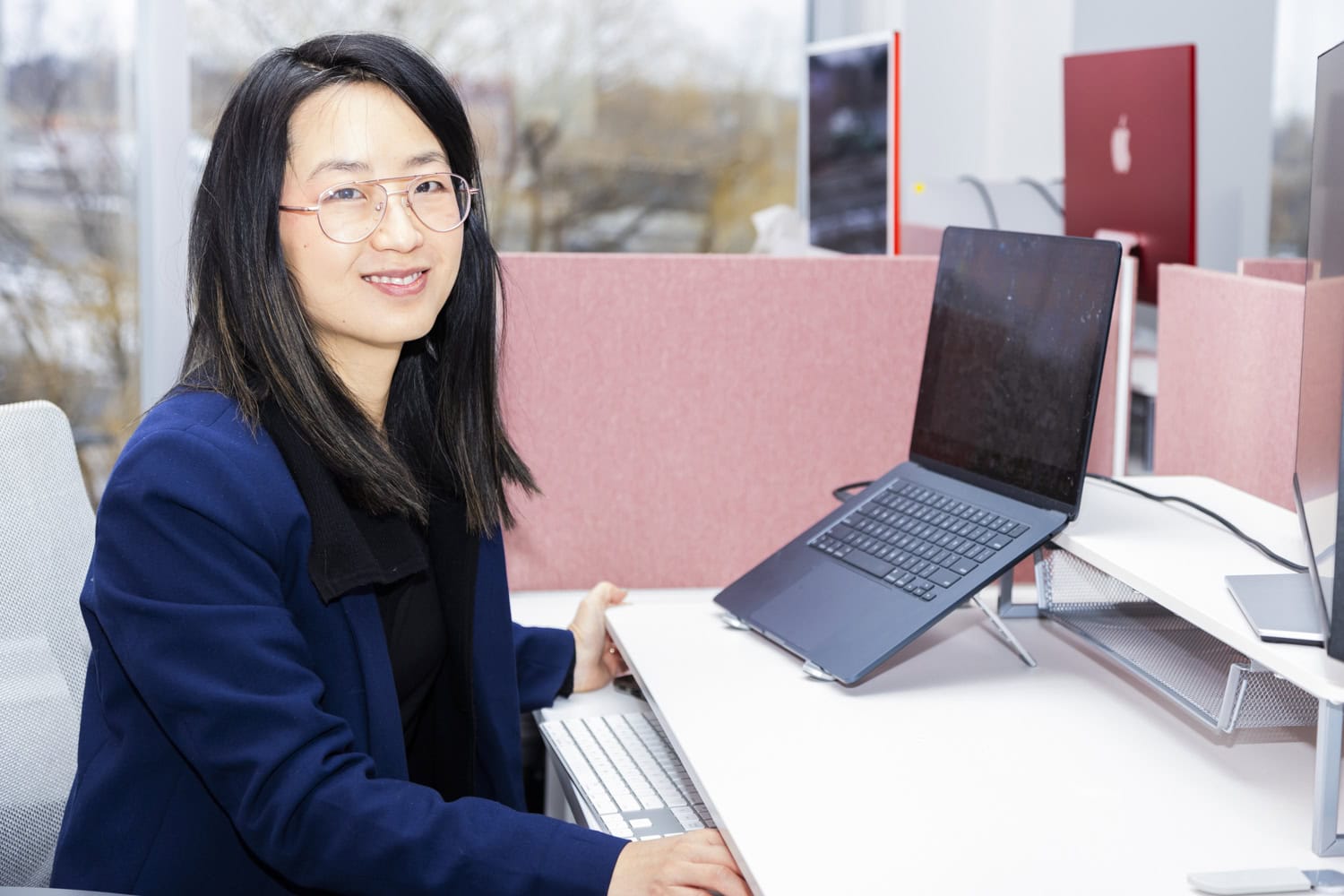 Junior Financial Analyst working at a desk with dual monitors and a laptop.
