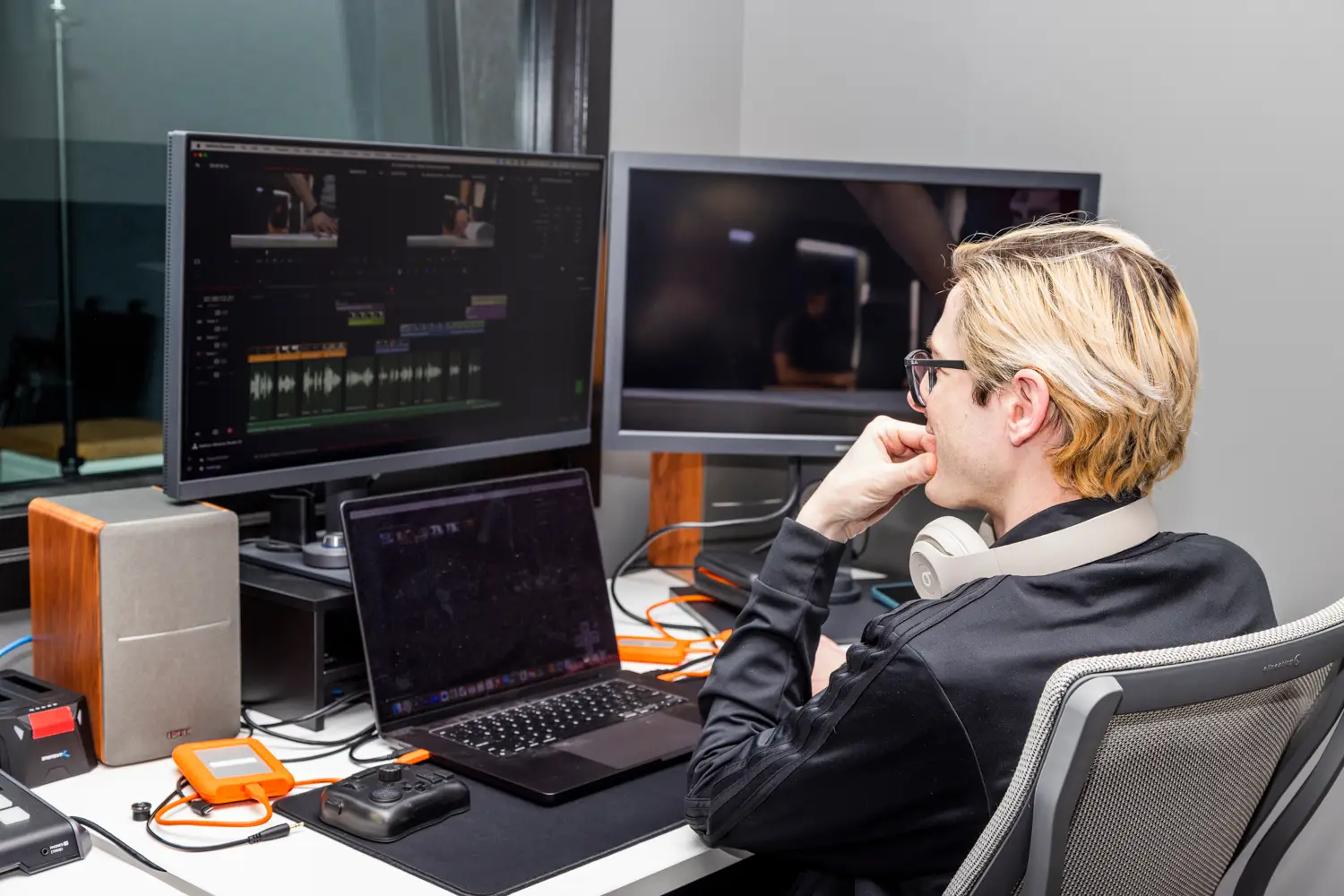 Video editing professional working on a computer with dual monitors in a professional office.