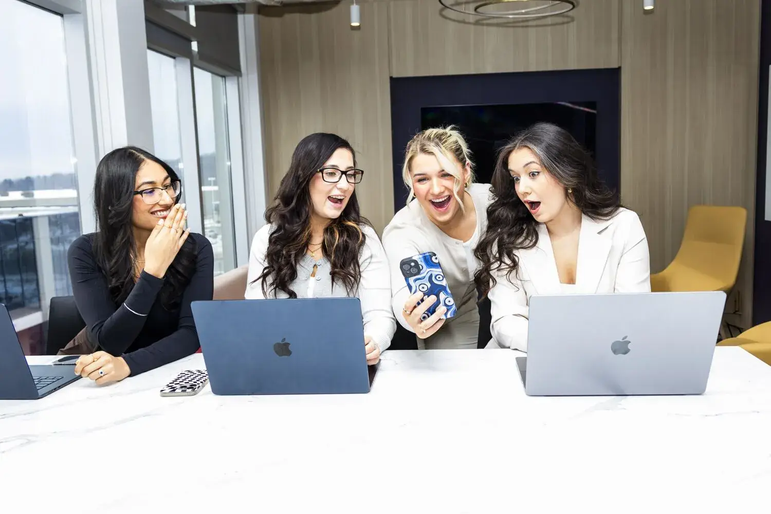 Women collaborating on a project with laptops in a bright, modern office.