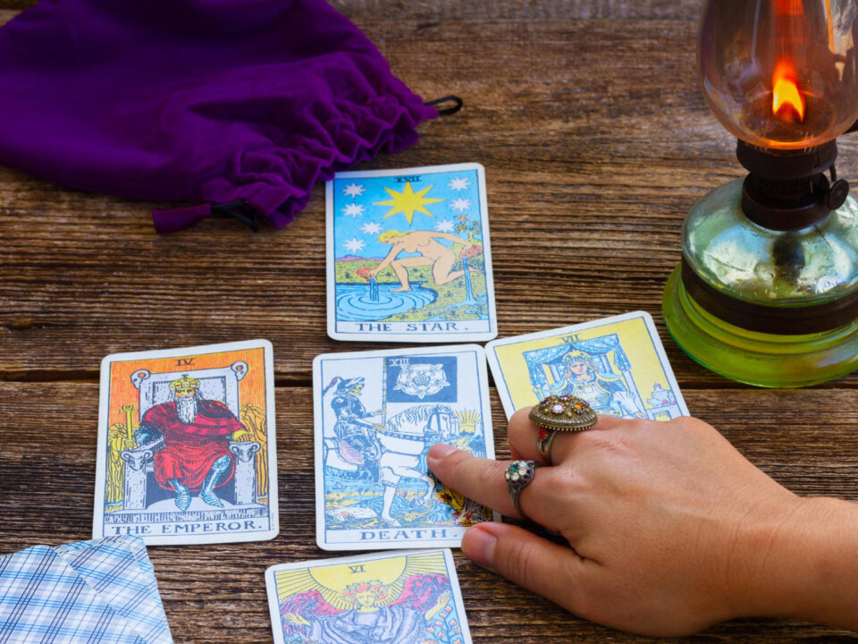 A person holding a tarot card with a candle and a hand