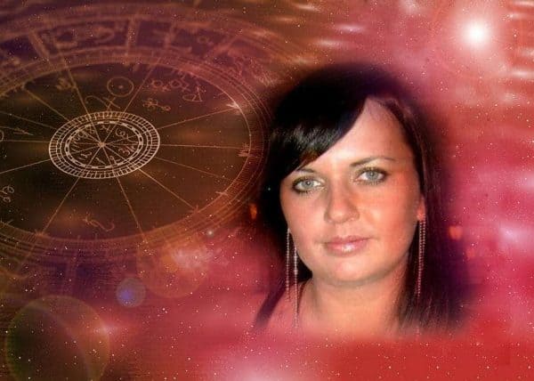 Donna con occhi azzurri e capelli scuri, sfondo mistico con simboli esoterici e carte dei tarocchi.