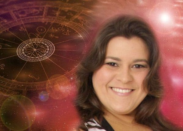 Donna sorridente con carte dei cartomanti e simboli zodiacali sullo sfondo cosmico.