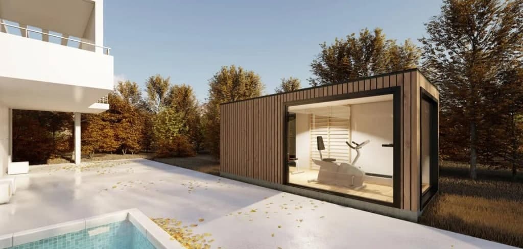 Gimnasio moderno junto a piscina y jardín otoñal.