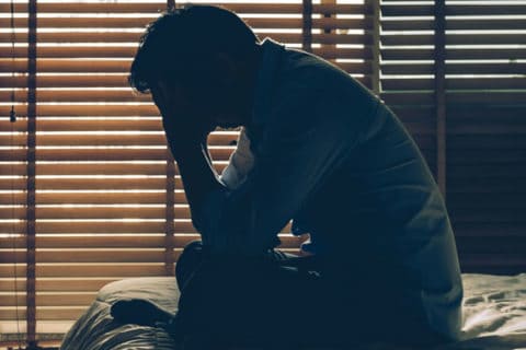 depressed man sitting on bed
