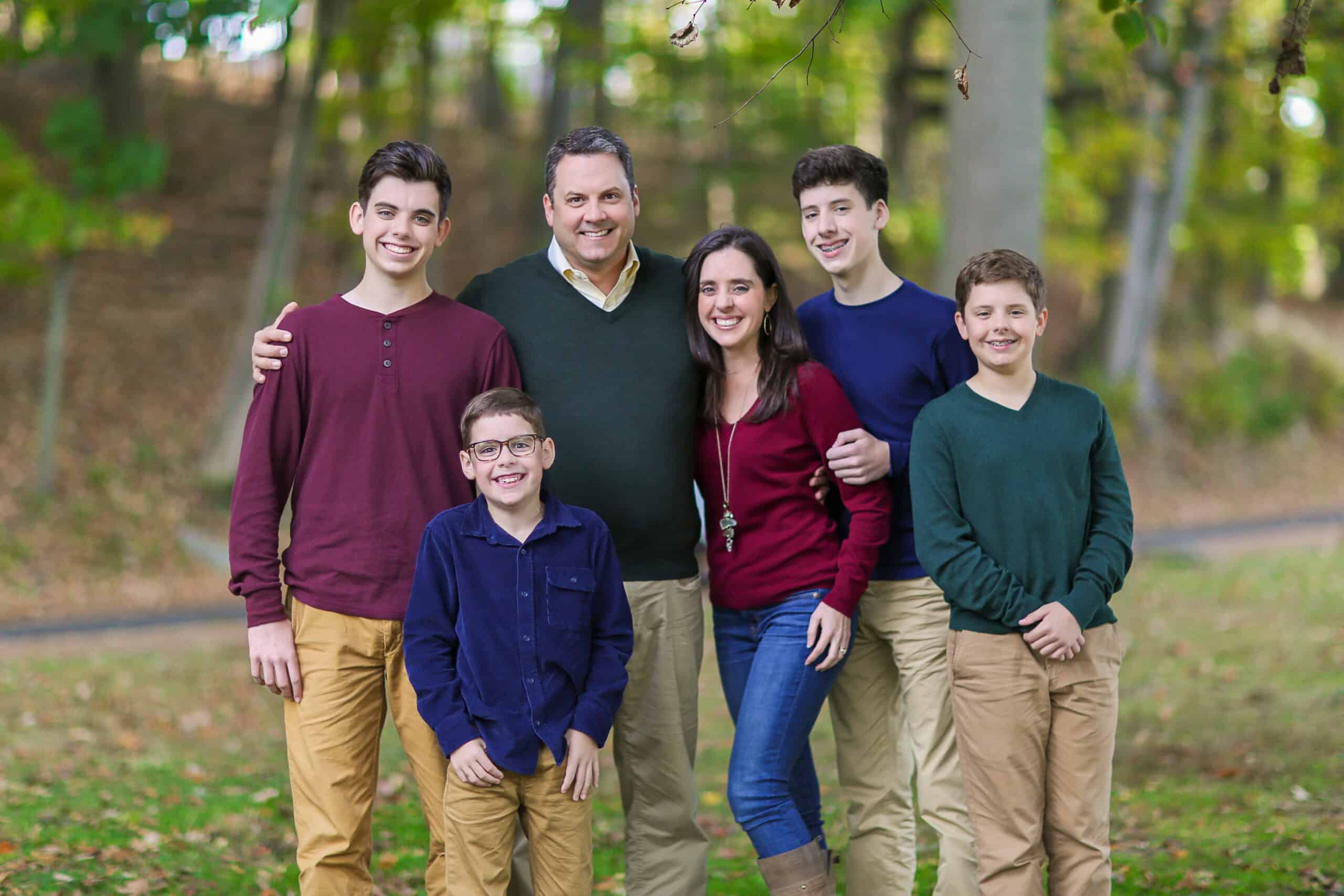Happy family portrait outdoors in a park, showing unity and love among parents and children.