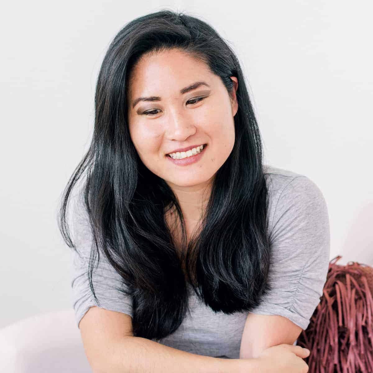 Confident Asian woman with long black hair smiling at the camera.