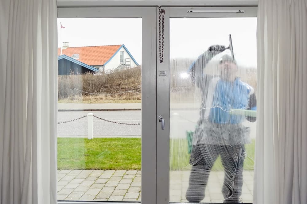 Vinduespudser arbejder på rene ruder i en bolig i Hillerød  – professionel vinduespolering fra CL Polering