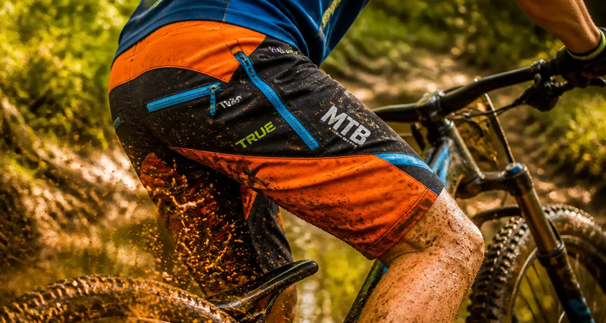 short vtt technique orange noir vététiste sentier