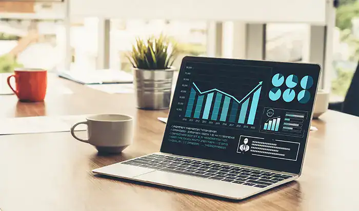 Laptop displaying financial graphs and analytics at a modern workspace.