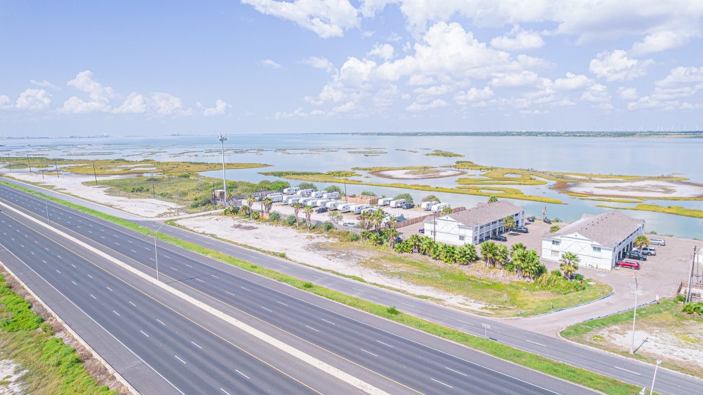 Portland, TX RV Park Aerial view of Portland TX coastal highway near wetlands and homes, close to Portland RV Park and Corpus Christi Boardwalk.