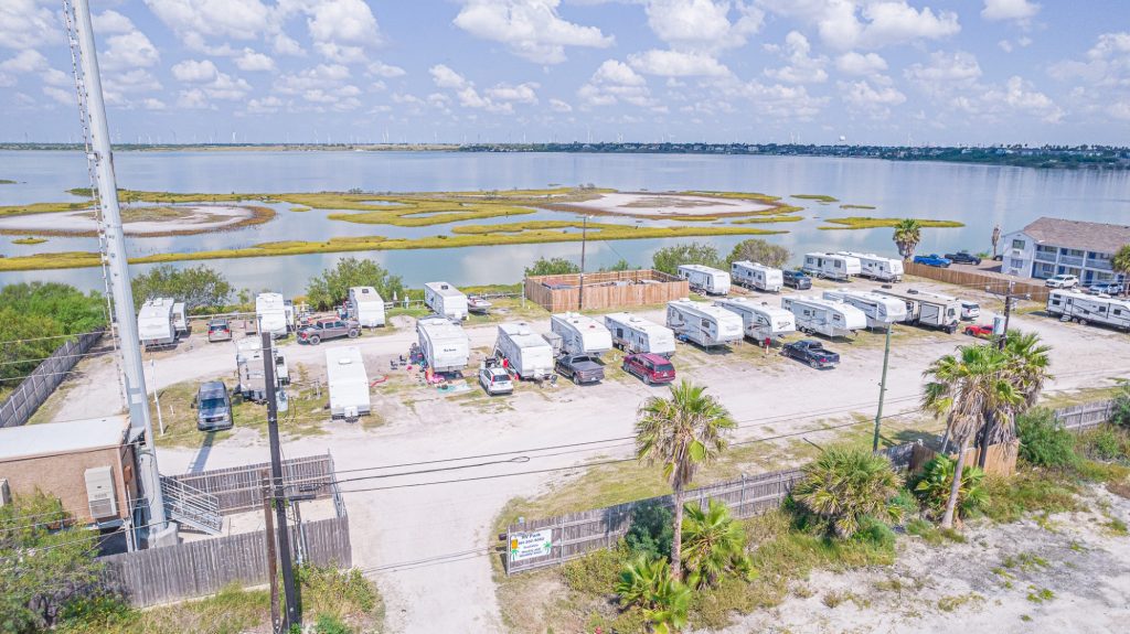 Portland, TX RV Park Aerial view of Portland RV Park, Portland, Texas with trailers, vehicles, palm trees, marshland near Corpus Christi Boardwalk.