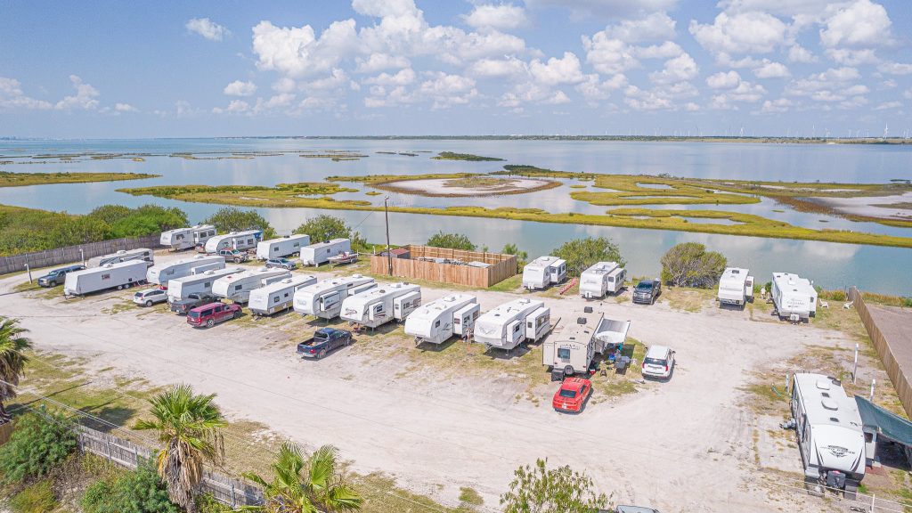 Portland, TX RV Park Aerial view of Portland RV Park, Portland Texas: trailers and cars on gravel by water, green islands, blue sky with clouds.
