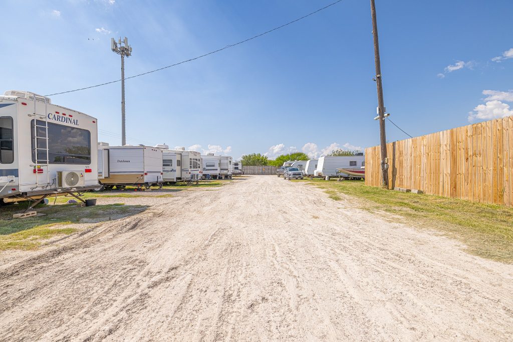 Portland, TX RV Park Portland RV Park in Portland, Texas with sandy road, parked RVs, grassy patches, wooden fence, utility pole and cell tower.