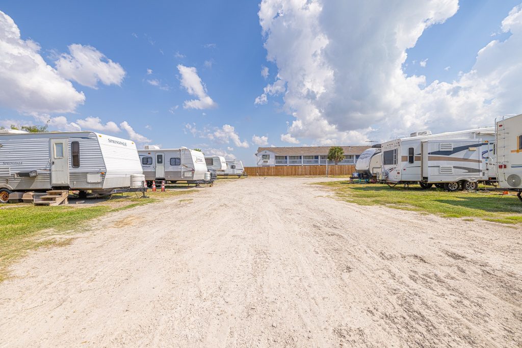 Portland, TX RV Park Portland RV Park in Portland, Texas features a sandy driveway lined with RVs, trailers, a two-story building, and blue sky.