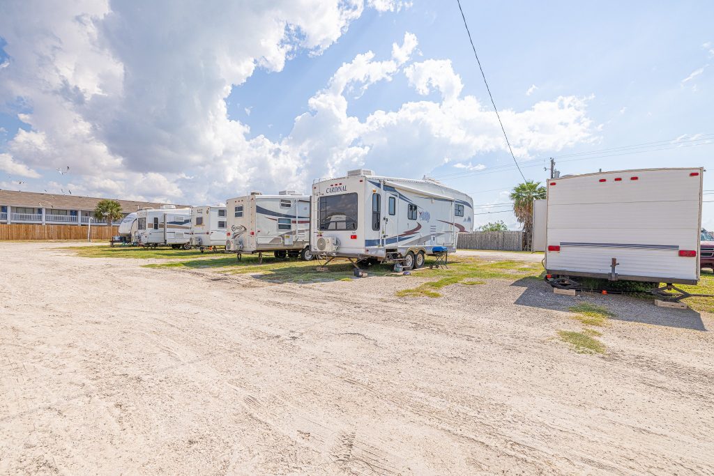 Portland, TX RV Park RVs and trailers parked at Portland RV Park in Portland, Texas, gravel lot, palm trees, near Corpus Christi Boardwalk.