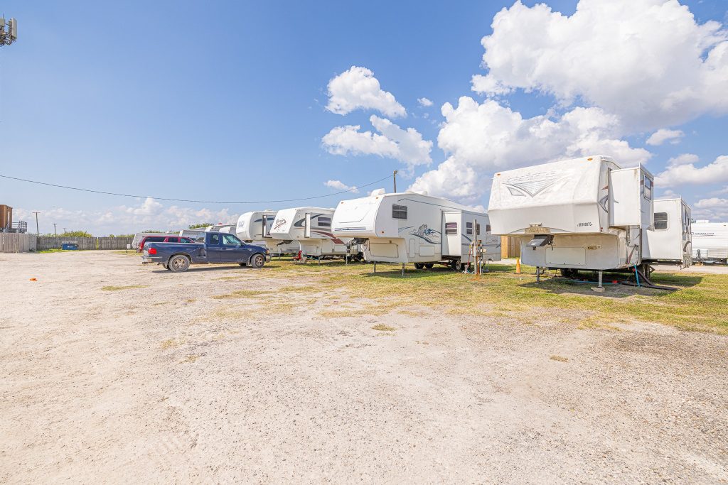 Portland, TX RV Park White RV trailers and a dark blue SUV parked on gravel at Portland RV Park in Portland, Texas under blue sky with clouds.